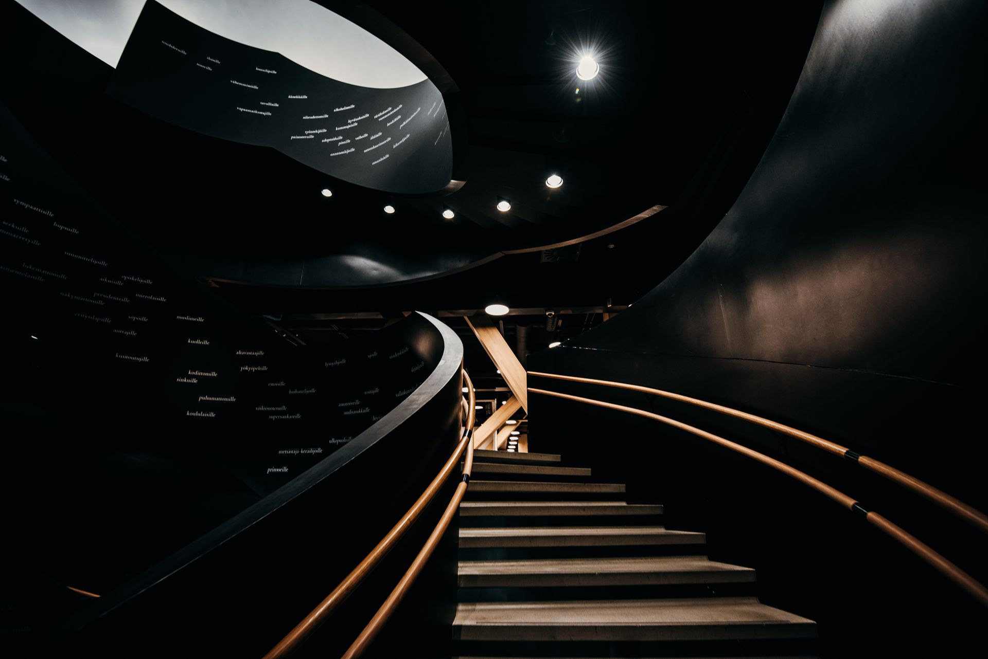 Sculptural staircase inside a dark, materially rich interior